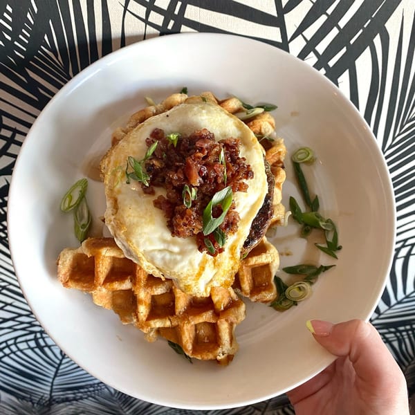 A Salted. On The Harbor waffle dish with a fried egg, bacon jam, and green onions.
