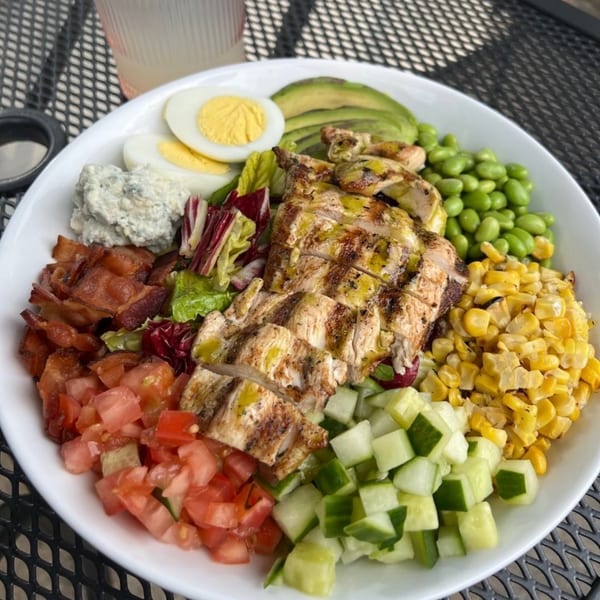 A vibrant Salted. On The Harbor Cobb salad with grilled chicken, bacon, egg, avocado, and corn.